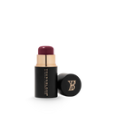 Cream blush stick in deep berry with black and gold tube, cap beside it