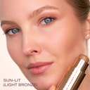 Pro Sculpt® Crème Contour Stick in light bronze beside a woman's face