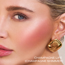 Pro Glow Crème Highlighter Stick in Champagne Life applied to cheekbone