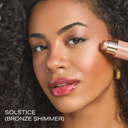 Pro Glow Crème Highlighter Stick with bronze shimmer applied to cheek